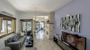 A living room with a sofa, coffee table, TV, and artwork.