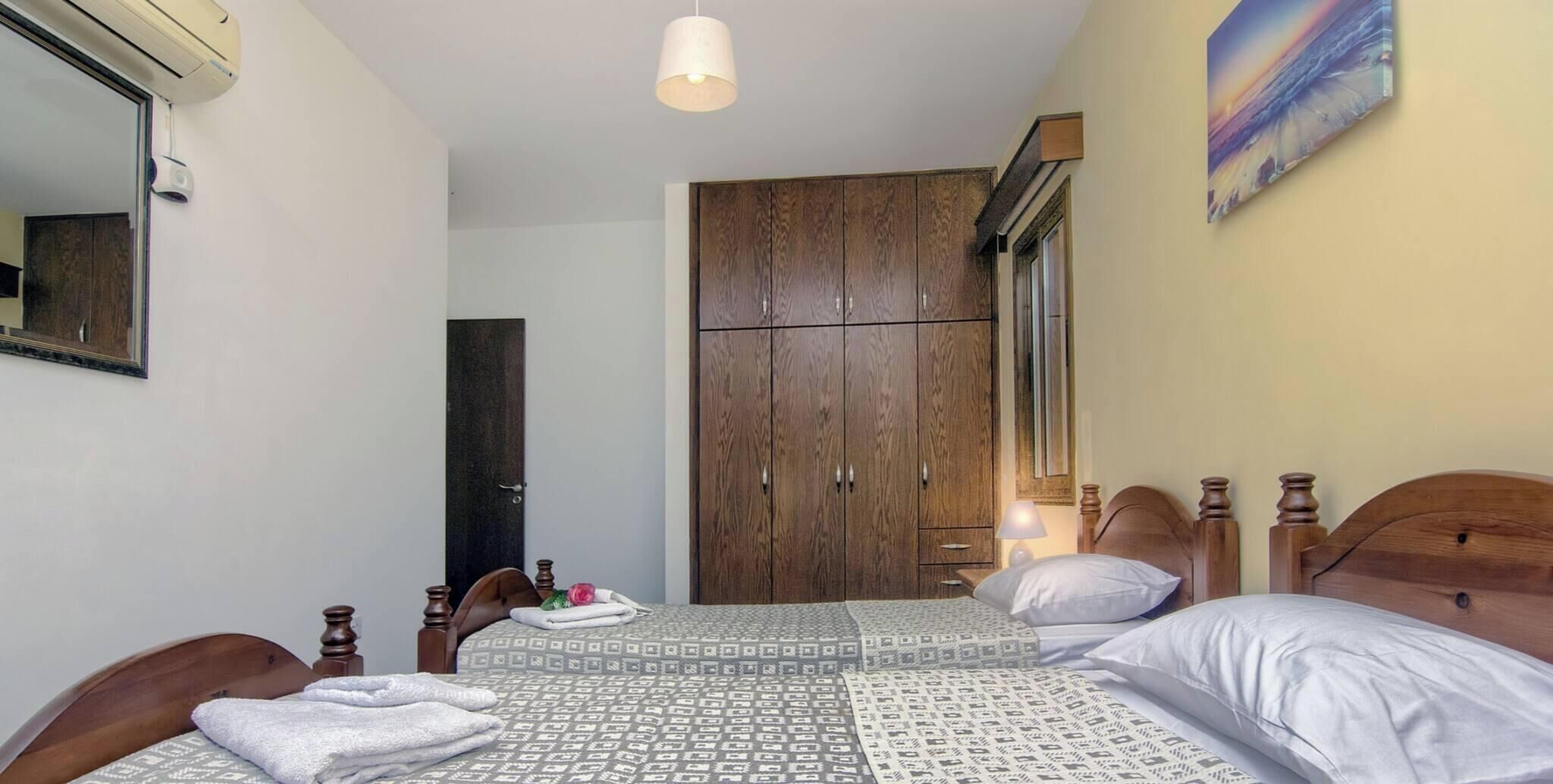 A bedroom with a bed, a wardrobe, a mirror, and a painting on the wall.