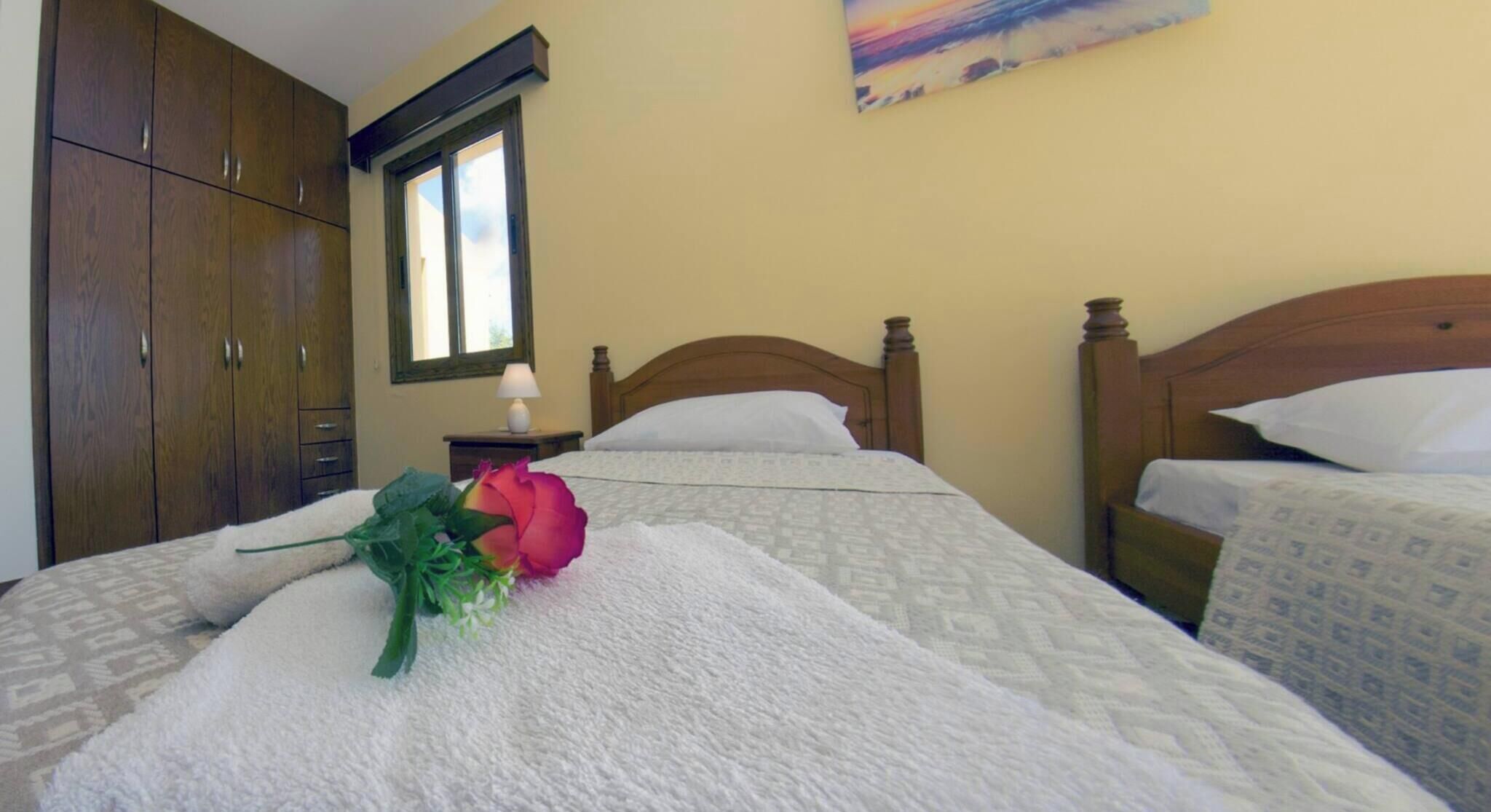Un dormitorio con cama, mesita de noche, ventana, armario y un cuadro en la pared.