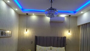 A modern bedroom with a large bed, two bedside tables, a chandelier, and an air conditioning unit. - Goistay Discover Unparalleled Elegance in the Clouds A Luxury Apartment in th (Santo Domingo)