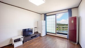 A modern hotel room with a large window, a flat-screen TV, a refrigerator, a microwave, and a cabinet. - Gangchon Beautiful pet House Pension (Chuncheon)