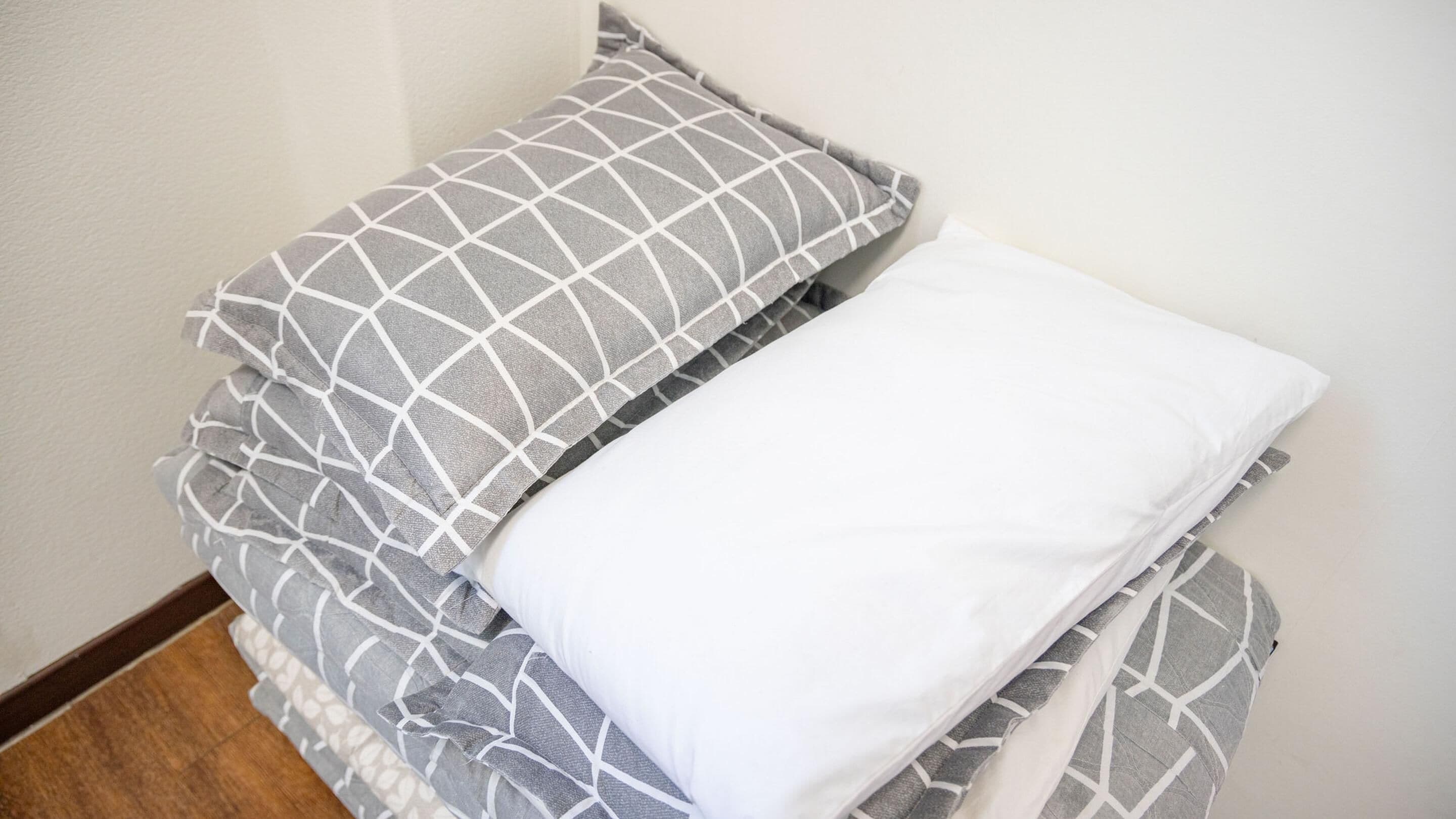 A neatly made bed with a patterned pillow and a plain white pillow.