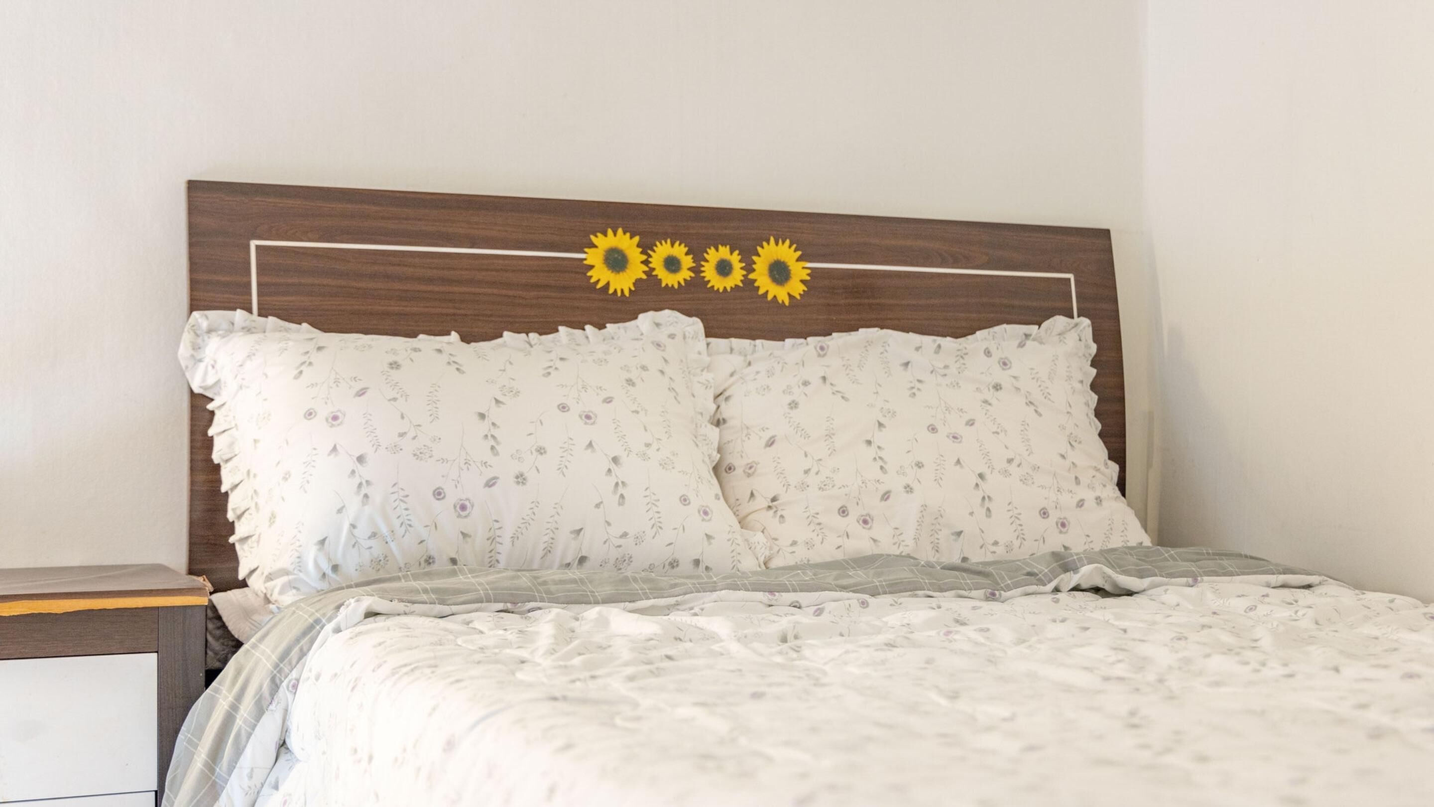 A bed with floral-patterned pillows and a headboard with sunflower decorations.