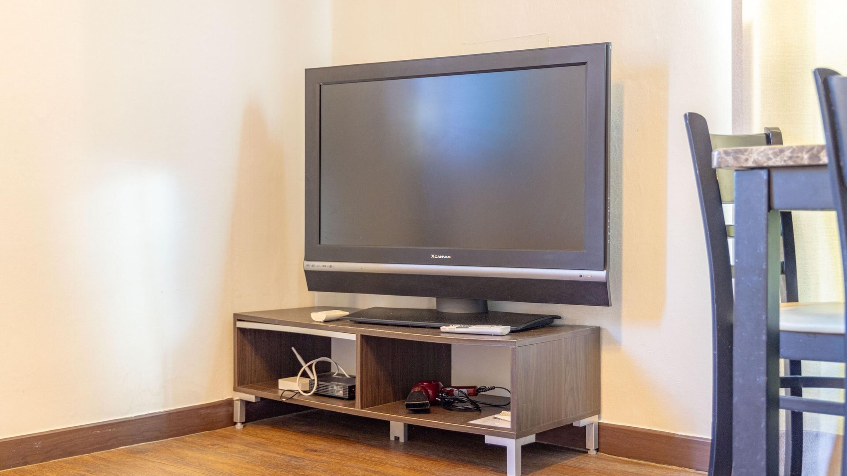 Een televisie op een standaard met afstandsbediening, een kleine speaker en een stekkerdoos.