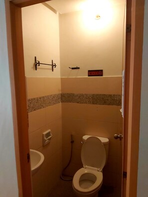 A small, compact bathroom with a toilet, sink, and a shower area. - OYO 916 Angel's Boardrooms (Quezon City)