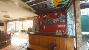 Un restaurant doté d’un bar en bois, de murs rouges et d’un sol carrelé.