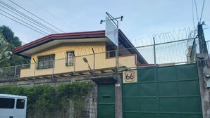 Un bâtiment avec une porte verte, une enseigne portant le numéro 66 et une clôture en fil de fer barbelé.
