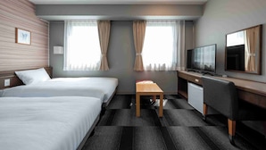 Habitación de hotel con dos camas, un escritorio con televisor, una mesita y una silla.