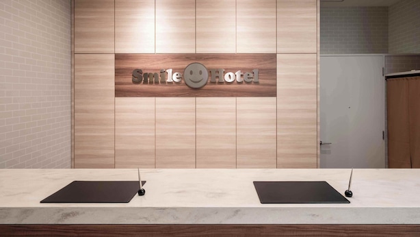 Un mostrador de recepción con un letrero que dice "Smile Hotel" y una cámara de seguridad encima.