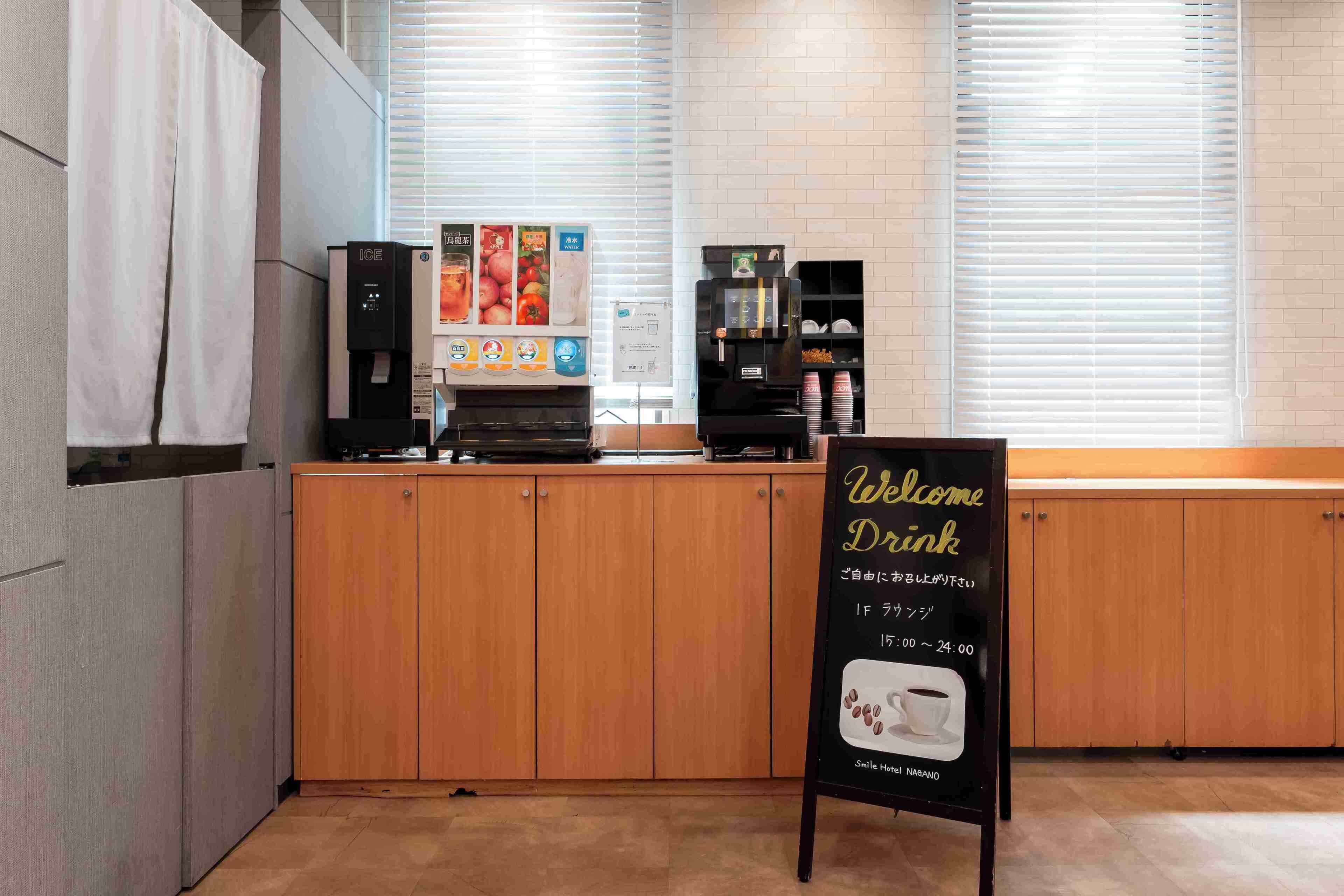 A coffee shop interior with a counter, coffee machines, and a sign welcoming visitors.