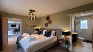 A modern bedroom with a large bed, bedside tables, a desk, and a shower area. - Eastgate Barn, Ashlin Farm Barns (Lincoln)