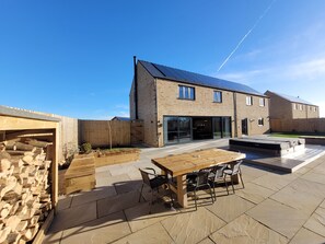 A modern house with a patio, a wooden table, and chairs.