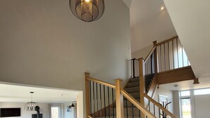 A spacious living area with a wooden staircase, a dining table, and a kitchen in the background. - Eastgate Barn, Ashlin Farm Barns (Lincoln)