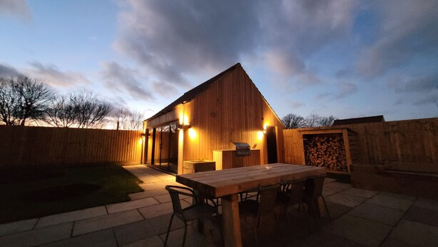 A wooden building with a patio area, a table, and chairs. - Lindum Barn, Ashlin Farm Barns (Lincoln)
