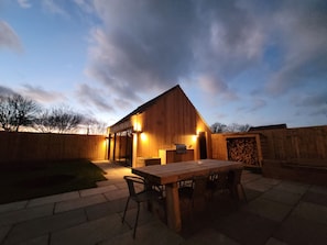 Een houten gebouw met een terras, een tafel en stoelen.