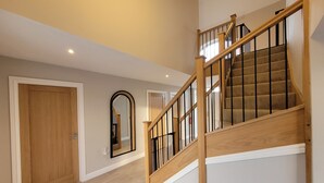 A modern interior with a wooden staircase, a mirror, and a door. - Lindum Barn, Ashlin Farm Barns (Lincoln)