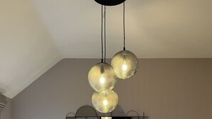 A modern bedroom with a large bed, two bedside tables, a decorative wall piece, and a unique ceiling light fixture. - Lindum Barn, Ashlin Farm Barns (Lincoln)