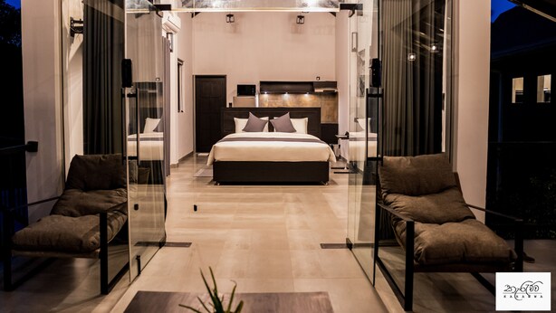 A modern bedroom with a large bed, glass doors, and a seating area. - Karawwa Luxury Villas  (Hikkaduwa)