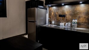 A modern kitchen with a stainless steel refrigerator, a microwave, and a sink area with water bottles and glasses. - Karawwa Luxury Villas  (Hikkaduwa)