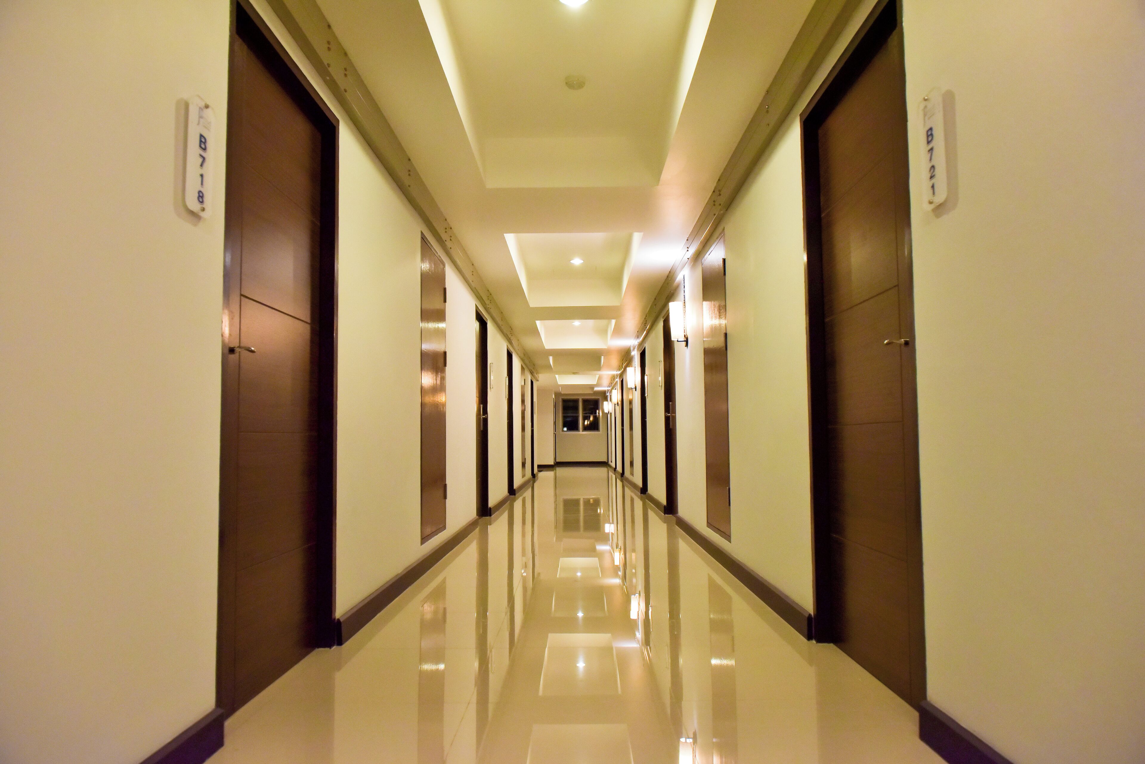 A long, well-lit hallway with doors on both sides, each marked with a number.