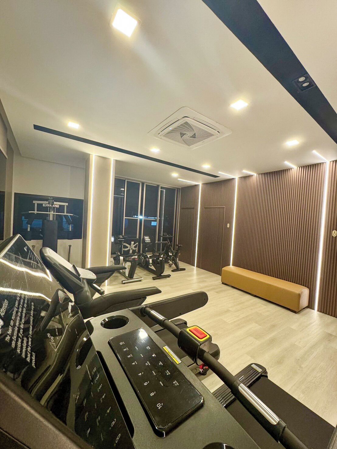 A modern gym with exercise equipment, a bench, and a large window.