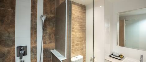 A modern bathroom with a glass shower enclosure, a white sink, and a mirror above it.