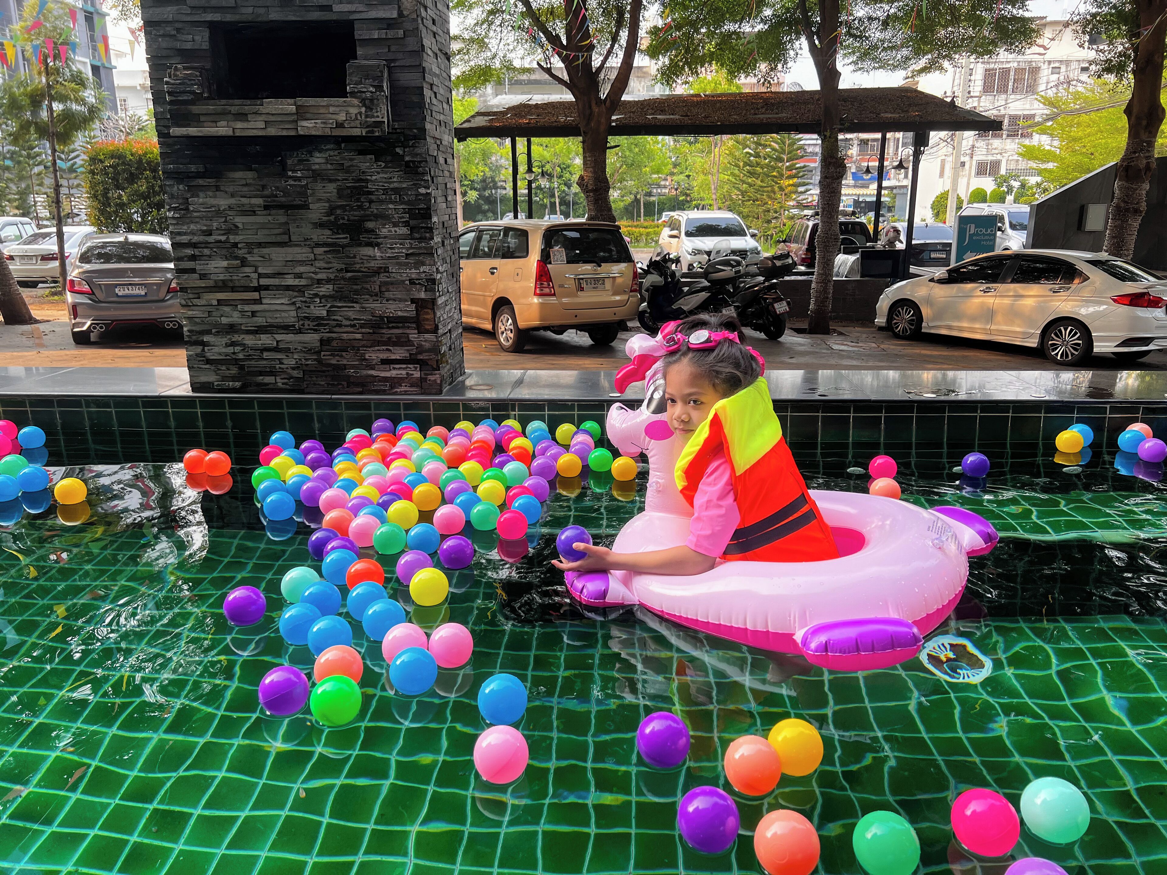 A pool with colorful balloons and a person in a pink inflatable float.