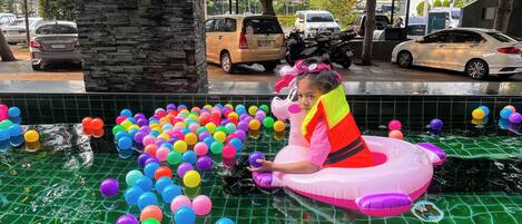 A pool with colorful balloons and a person in a pink inflatable float.