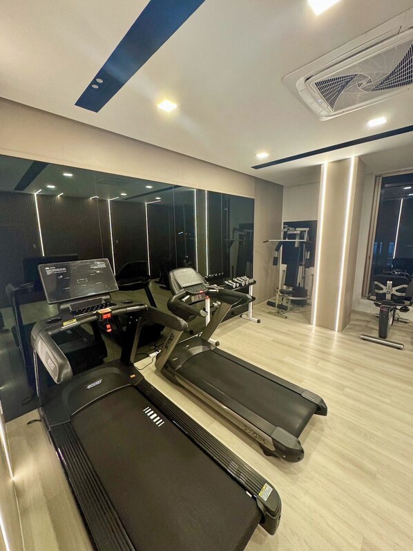 Un gimnasio moderno con cintas de correr, un espejo grande y un muro con espejos.