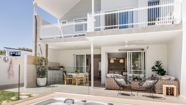 Une maison à deux étages dotée d’un balcon, d’un jacuzzi et d’un espace salon extérieur.