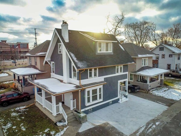 A two-story house with a covered front porch, a garage, and a driveway.
