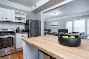 A modern kitchen with white cabinetry, a stainless steel refrigerator, and a wooden countertop.