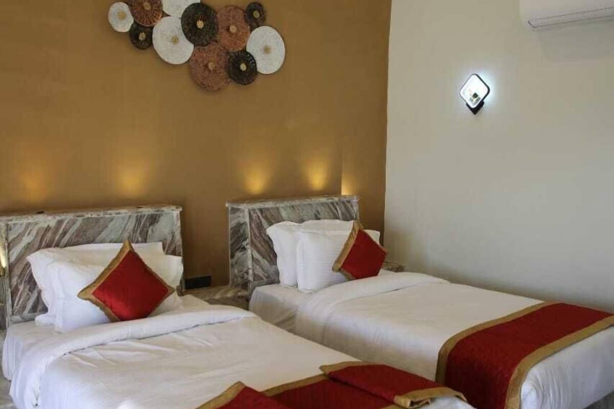 A hotel room with two beds, marble headboards, a wall-mounted light fixture, and a decorative wall piece.