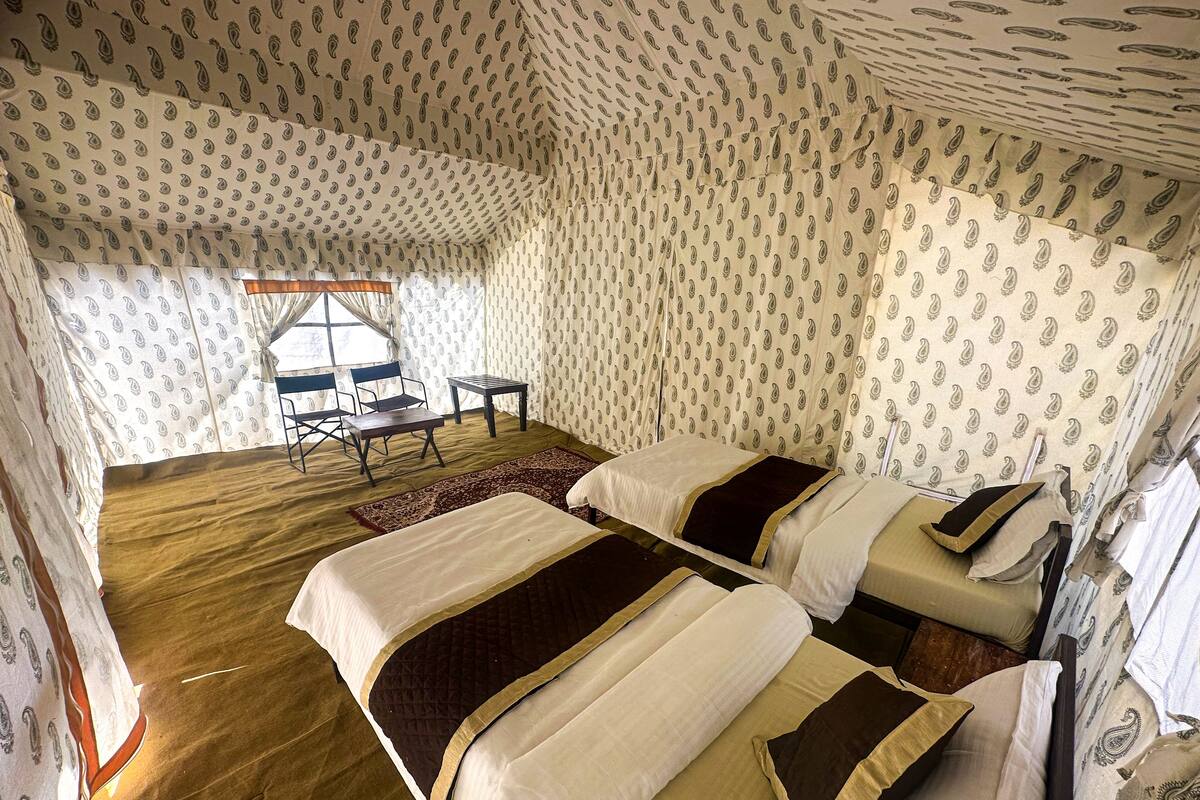 A room with two beds, a small table, and a chair.