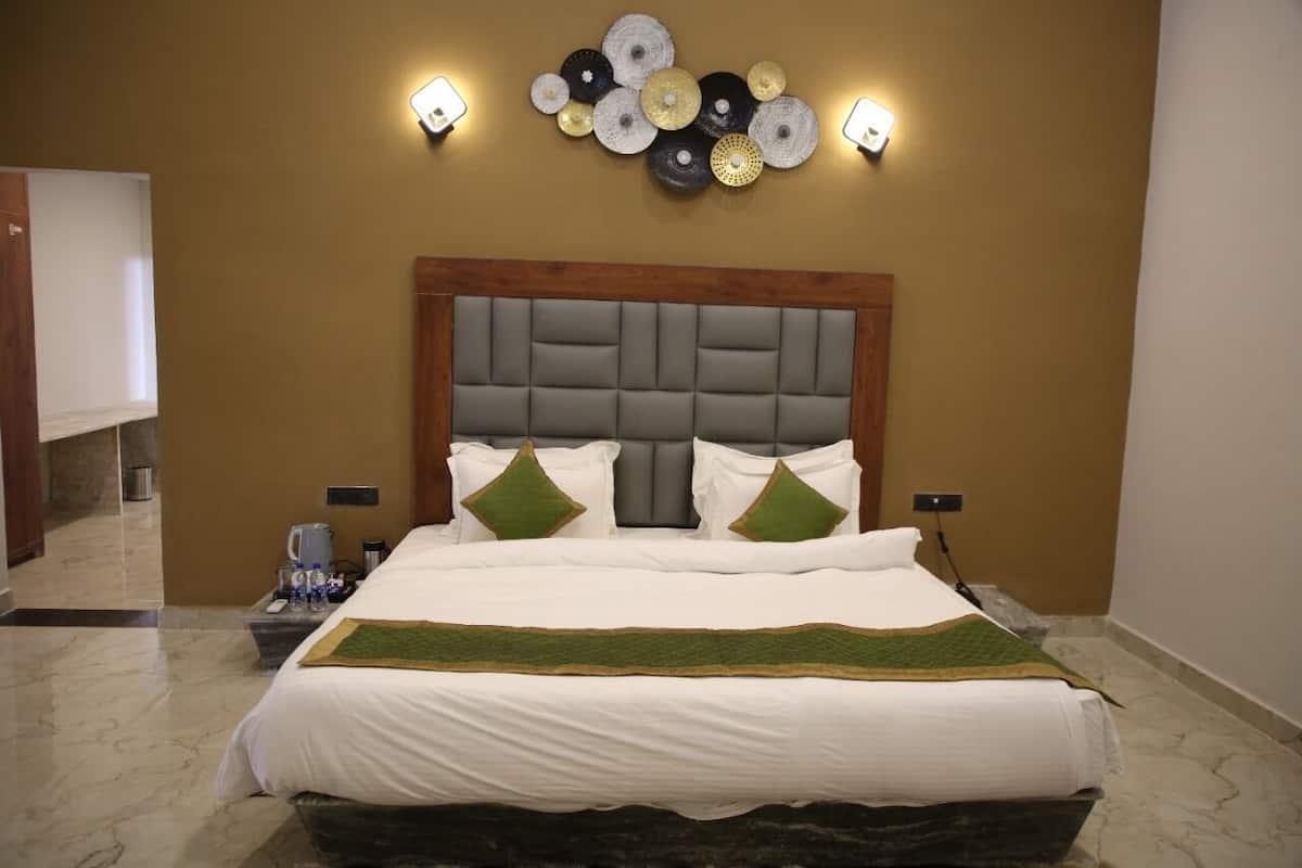 A hotel room with a large bed, a wooden headboard, and a wall-mounted light fixture.
