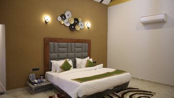 Une chambre d’hôtel comprenant un lit, une table de chevet, un climatiseur fixé au mur, des éléments décoratifs sur les murs et un luminaire.