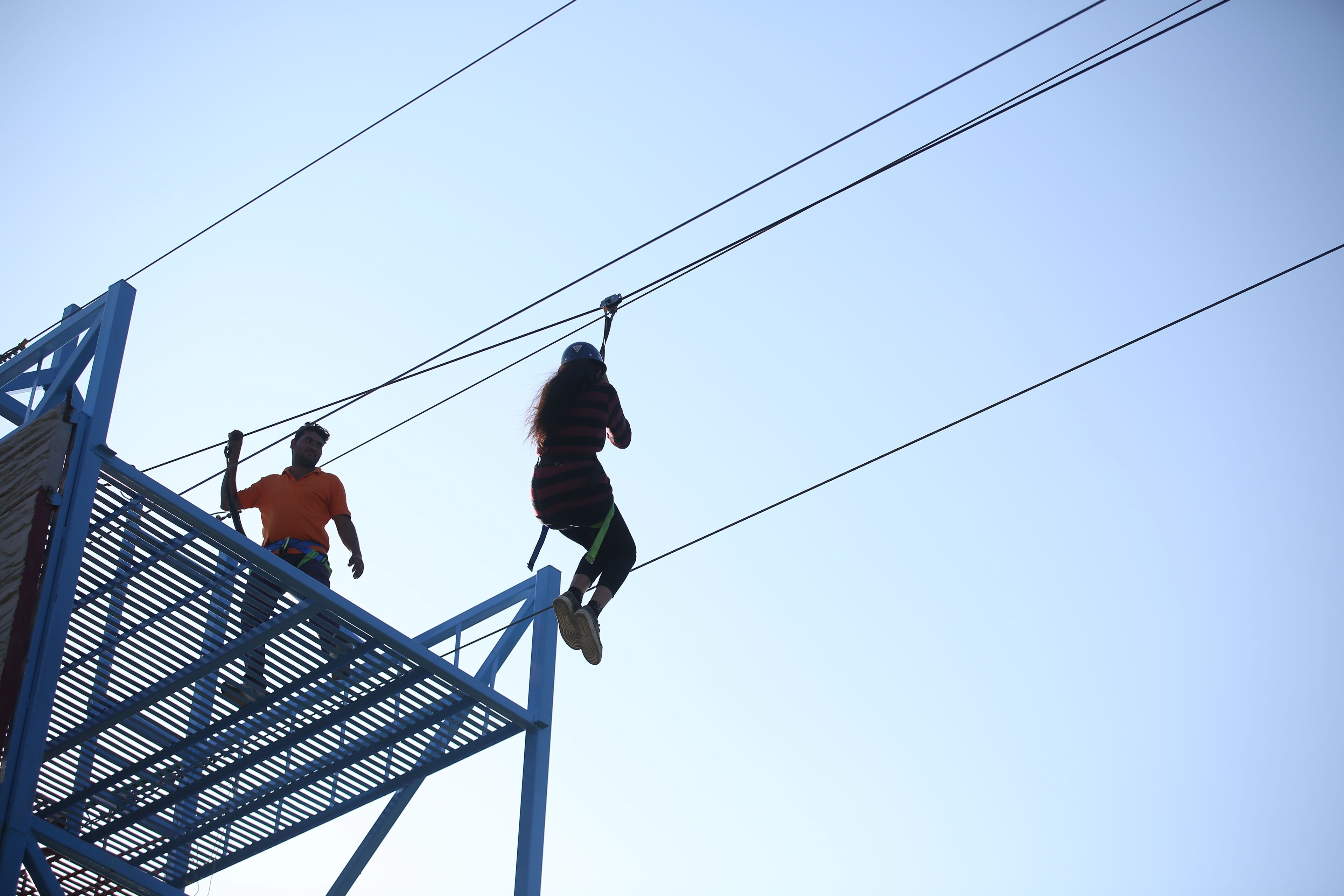 A person bungee jumping from a high structure with metal railings.