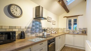 A modern kitchen with a microwave, kettle, and oven. There is a clock on the wall and a window with a view. - Duddon View  -  Duddon Valley, Lake District (Dog-friendly) (Seathwaite)