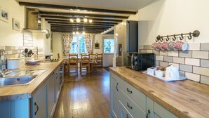 A kitchen with wooden countertops, a built-in sink, and a dining area with chairs and a table. - Riverside Cottage  - Duddon Valley (Dog-friendly) (Seathwaite)