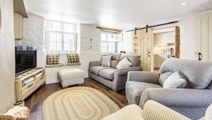 A cozy living room with a sofa set, a television, and a wooden floor.
