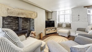 A cozy living room with a stone fireplace, a television, and comfortable seating.