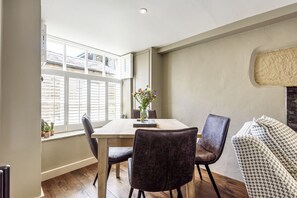 A dining area with a table, chairs, and a vase of flowers.