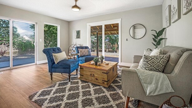 A spacious living room with a blue armchair, a grey sofa, and a wooden chest of drawers.
