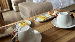 A hotel room with two beds, a wooden table with breakfast items, and a framed picture on the wall. - Park Otel (Düzce)