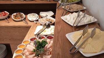 A buffet table with various food items including fruits, cheeses, and dips.