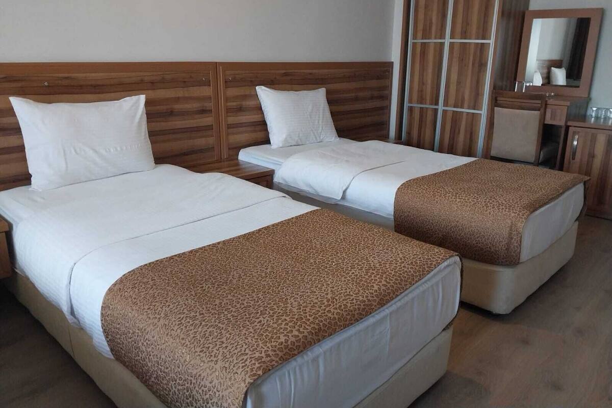 A hotel room with two beds, a wardrobe, a desk, and a mirror.