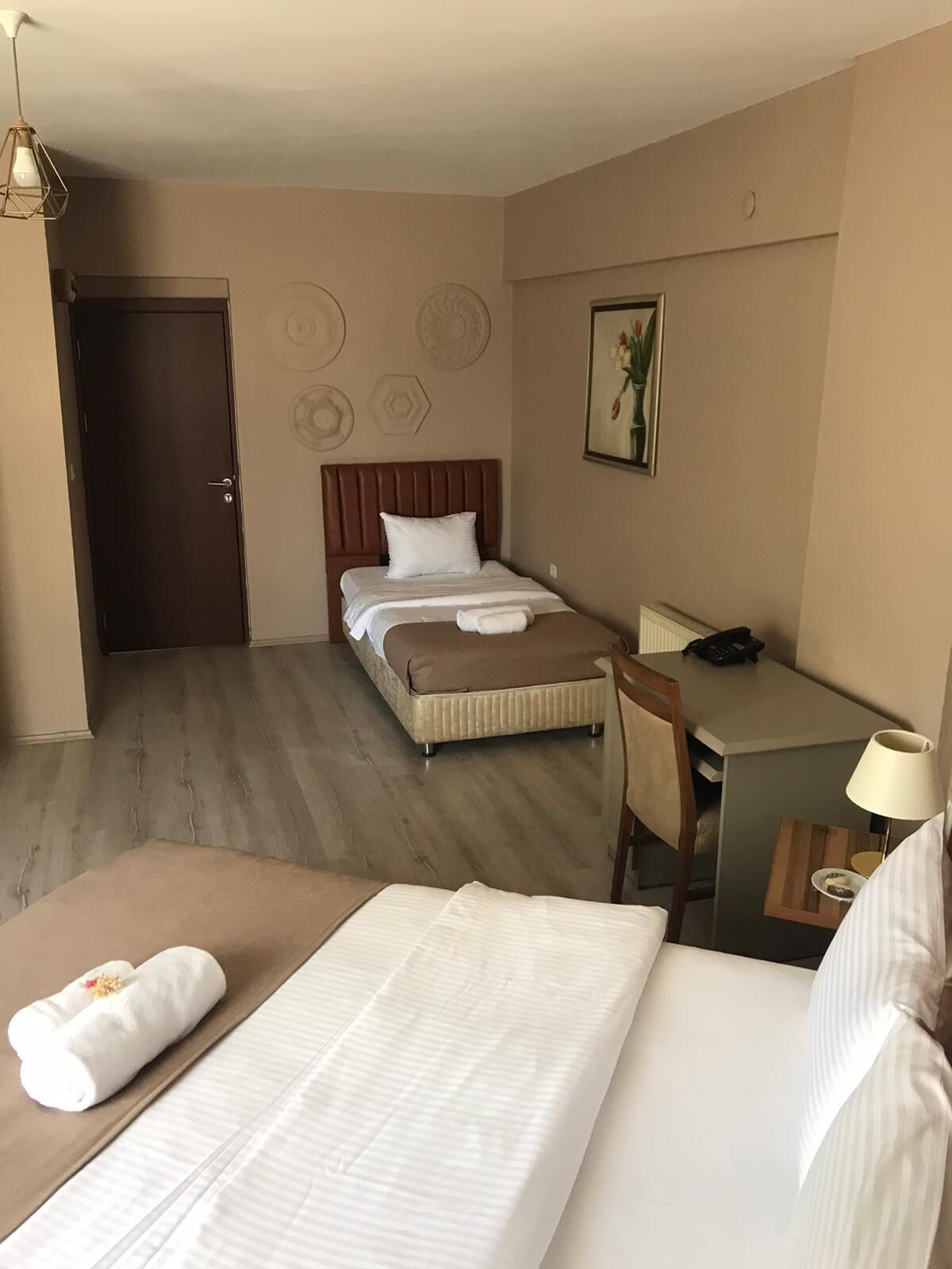 Ein Hotelzimmer mit zwei Betten, einem Schreibtisch, einem Stuhl, einer Lampe und einer Tür.