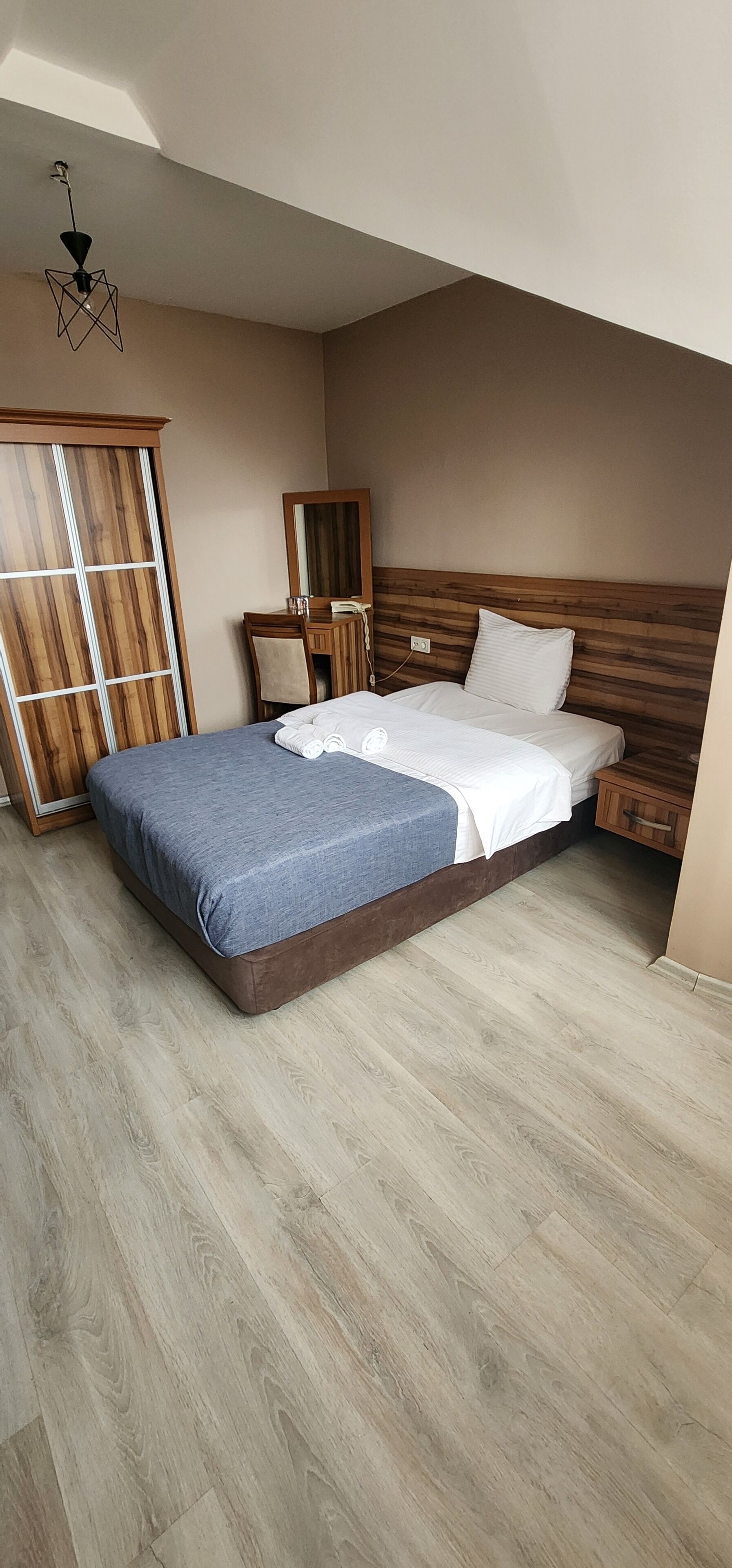 Un dormitorio con cama, cabecera de madera, armario y escritorio con espejo.