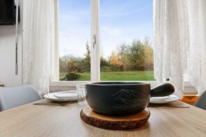 A meditation bowl on a wooden coaster on a table by a window with a view of a grassy field.