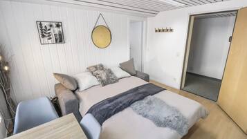 Un dormitorio moderno con una cama, mesitas de noche, un espejo circular colgante y una obra de arte en la pared.